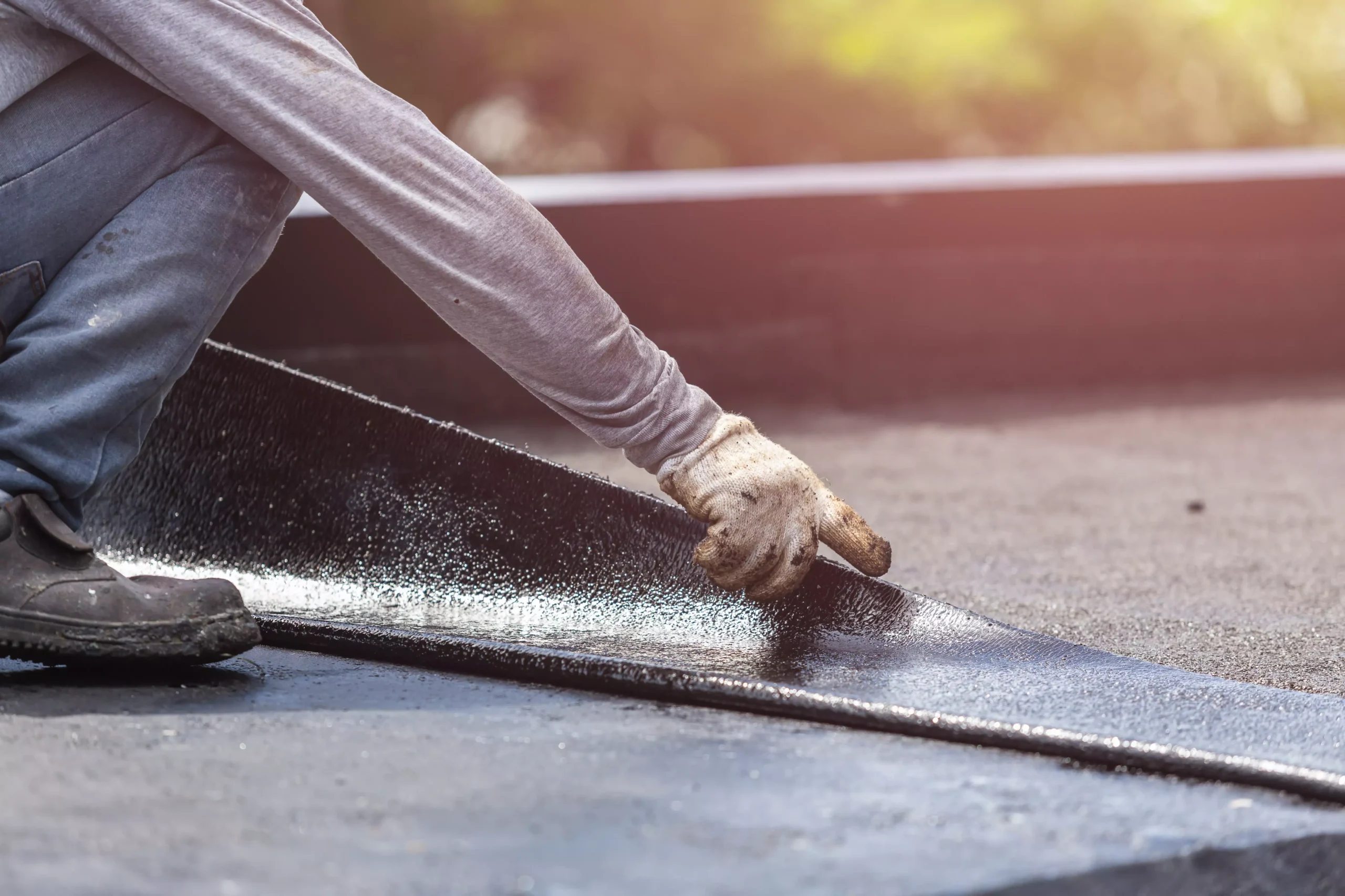Commercial roofer installing waterproof roofing membrane on a flat roof